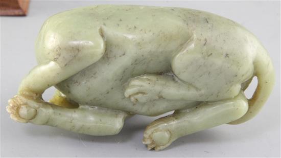 A Chinese green jade figure of a recumbent dog, length 12.5cm excl. wood stand